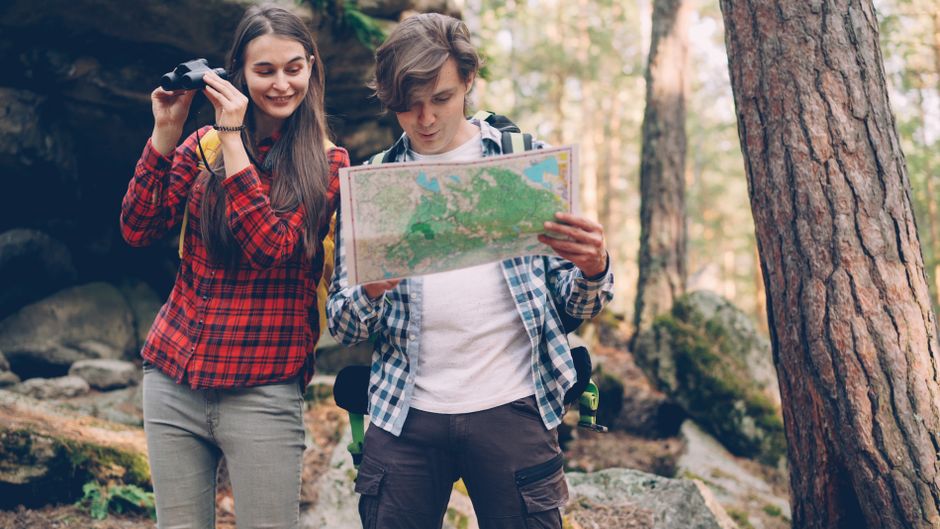 Two young hikers use a map in a forest adventure.